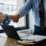 Life sciences startup founder and partner shaking hands after negotiating a licensing agreement for technology growth